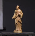 Wooden statue of a religious figure on a dark background
