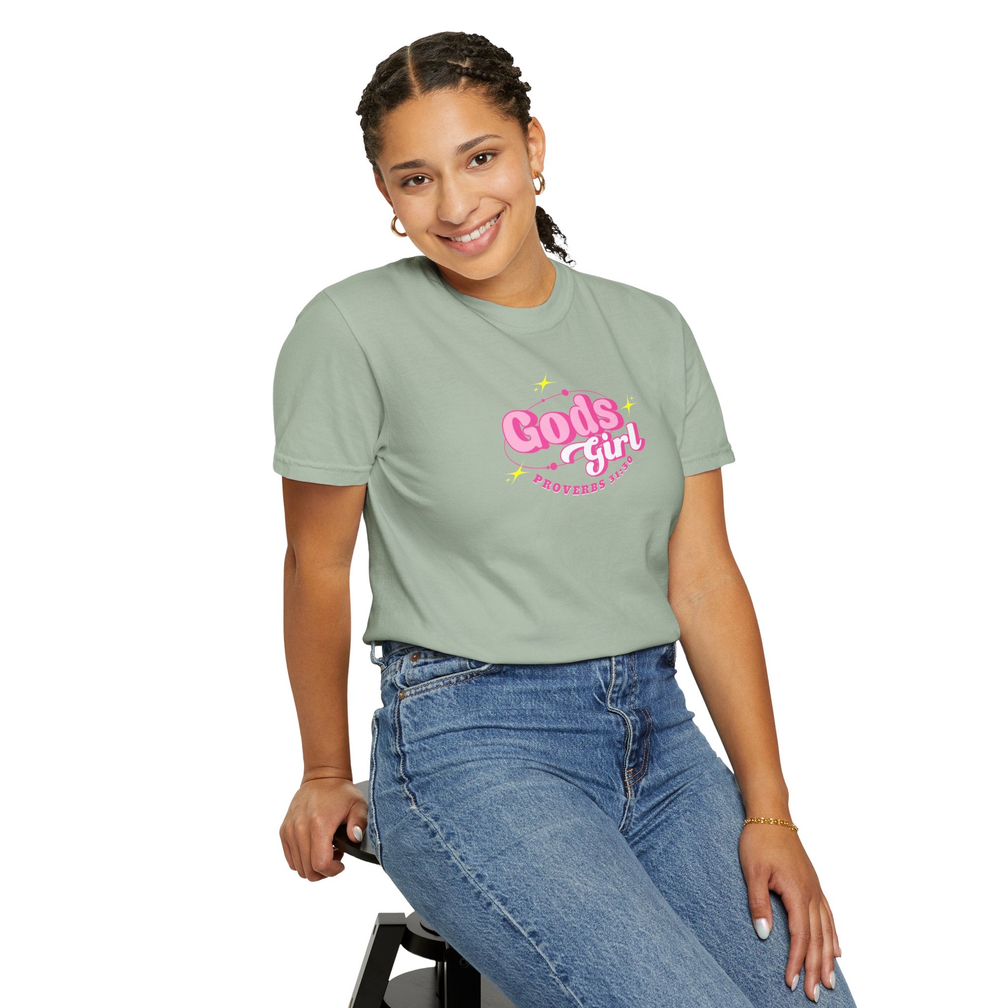 Person wearing a light green t-shirt with 'God's girl' text, sitting on a stool against a white background