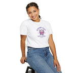Person wearing a white t-shirt with a graphic design and text, sitting on a stool against a white background.