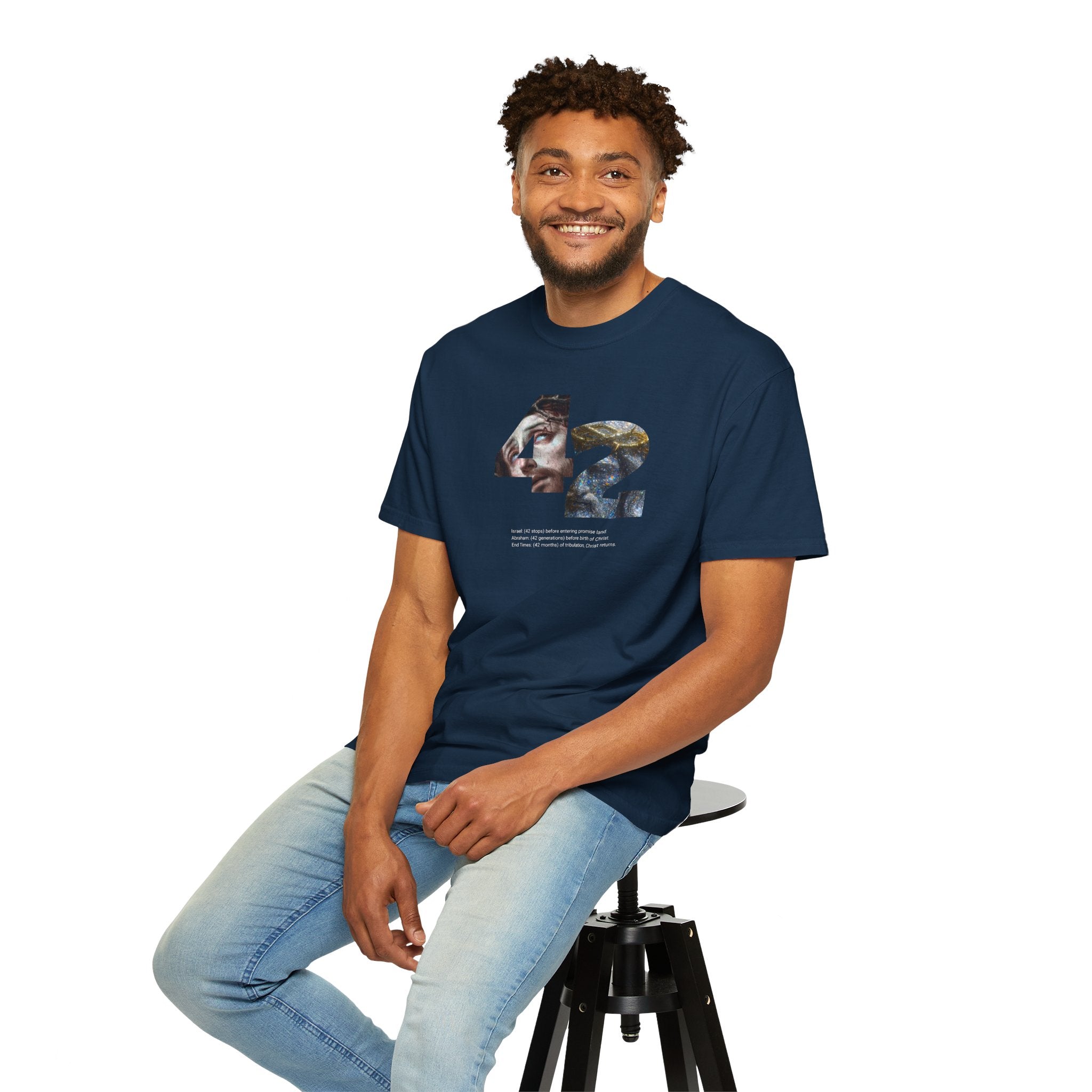 Man sitting on a stool wearing a navy blue t-shirt with a logo on a white background
