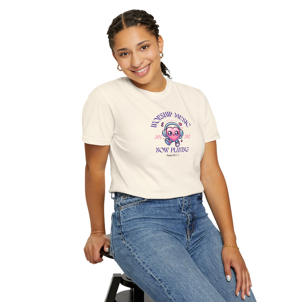 Person wearing a white t-shirt with a graphic design and text, sitting on a stool against a white background.