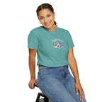 Person wearing a teal t-shirt with text sitting on a stool against a white background