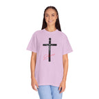 Person wearing a light purple t-shirt with a black cross design and pink text on a white background