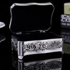Silver jewelry box with floral designs on a black background