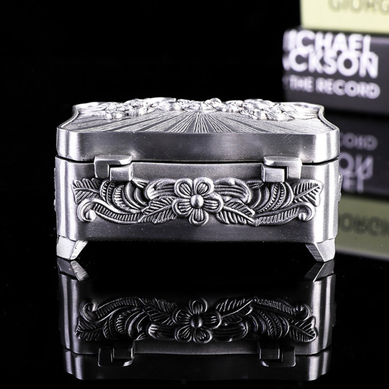 Decorative silver box with intricate designs on a black background