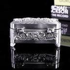 Decorative silver box with intricate designs on a black background