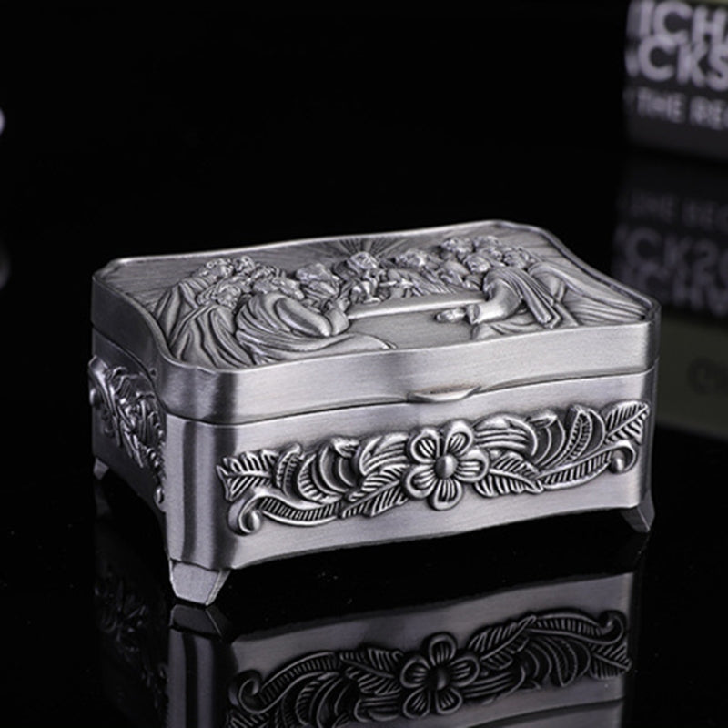 Decorative silver box with floral patterns on a black background