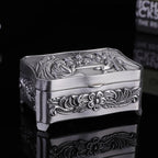 Decorative silver box with floral patterns on a black background
