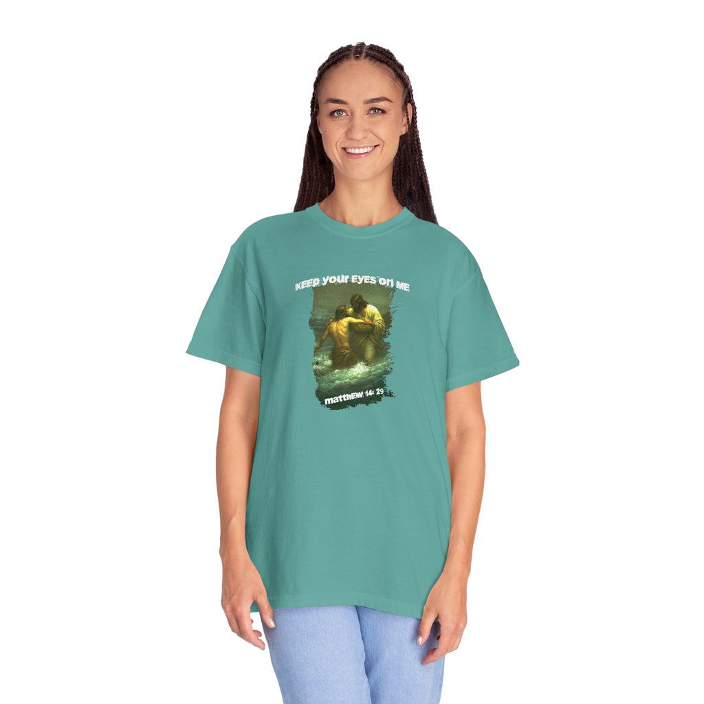 Person wearing a teal t-shirt with a graphic design and text on a white background