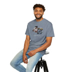 Man sitting on a stool wearing a gray t-shirt and light blue jeans against a white background