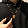 Gold necklace with a pendant worn by a person in a black turtleneck.