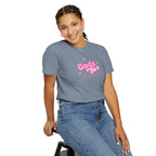 Person wearing a gray t-shirt with 'Gods Girl' text, sitting on a stool against a white background