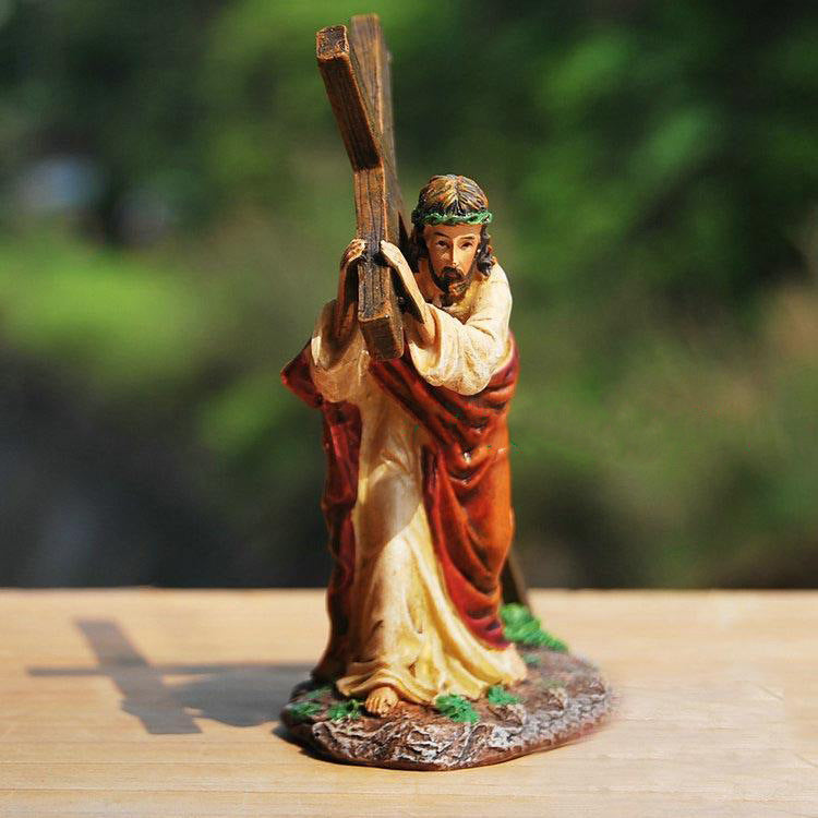 Statue of a figure carrying a cross on a wooden surface with a blurred green background
