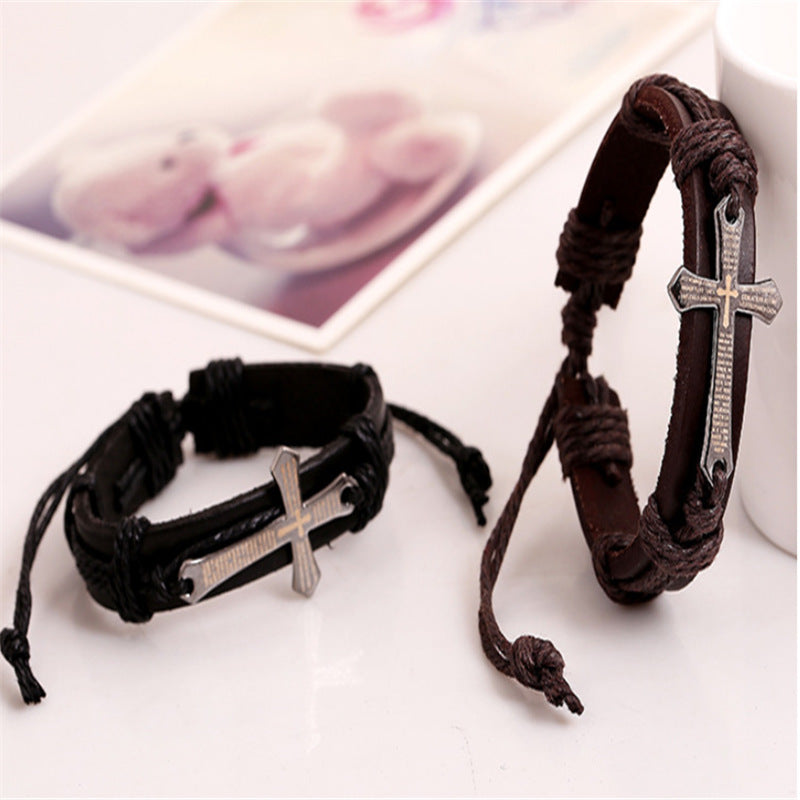 Two leather bracelets with silver cross charms on a light surface.