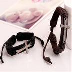 Two leather bracelets with silver cross charms on a light surface.