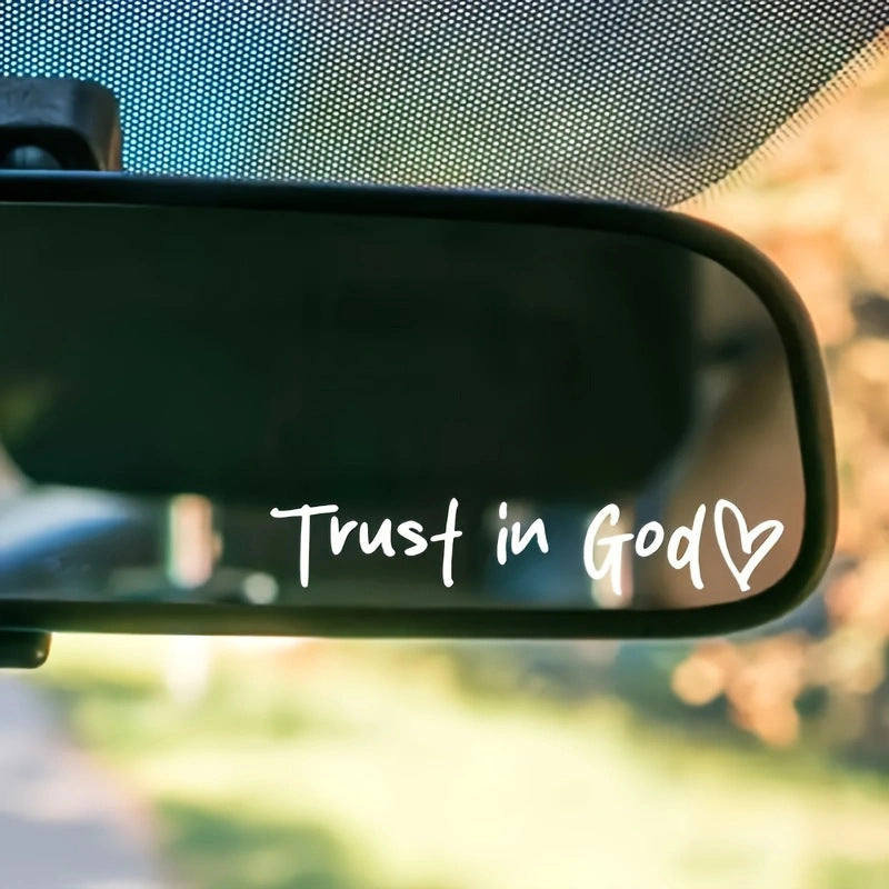 Car rearview mirror with 'Trust in God' text and heart symbol