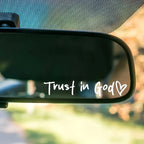 Car rearview mirror with 'Trust in God' text and heart symbol