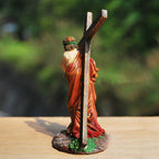 Statue of a person carrying a cross on a wooden surface with a blurred green background