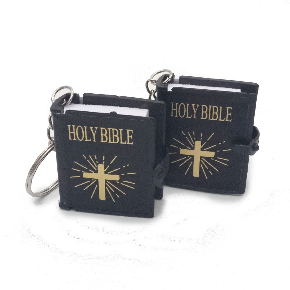 Two black keychains with 'HOLY BIBLE' text and gold crosses on a white background