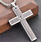 Silver cross pendant with engraved text on a wooden block