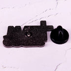 Black glittery 'MAD' pin on a white marble background
