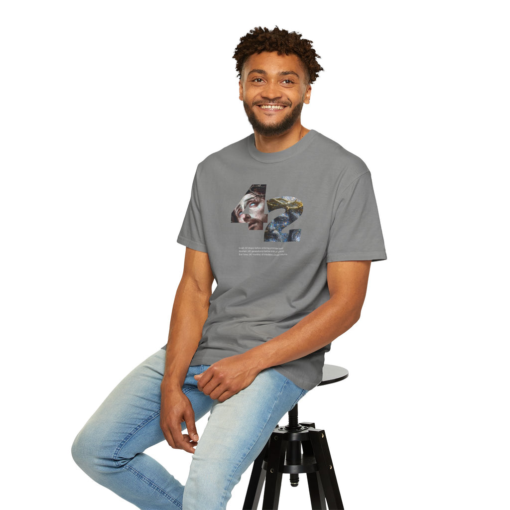 Man wearing a gray t-shirt with text, sitting on a stool against a white background