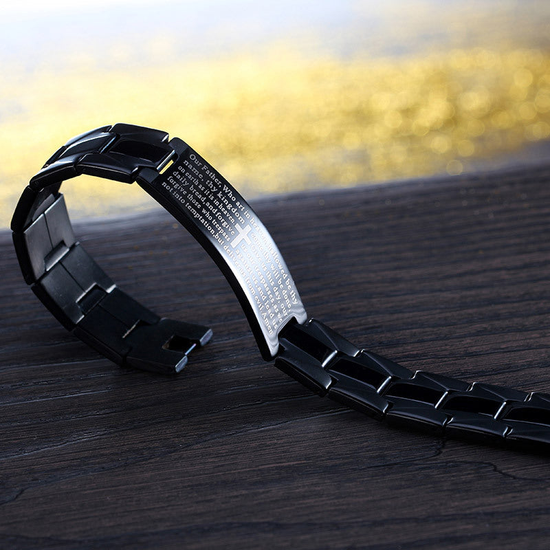 Black metal watch strap on a wooden surface with a blurred yellow background