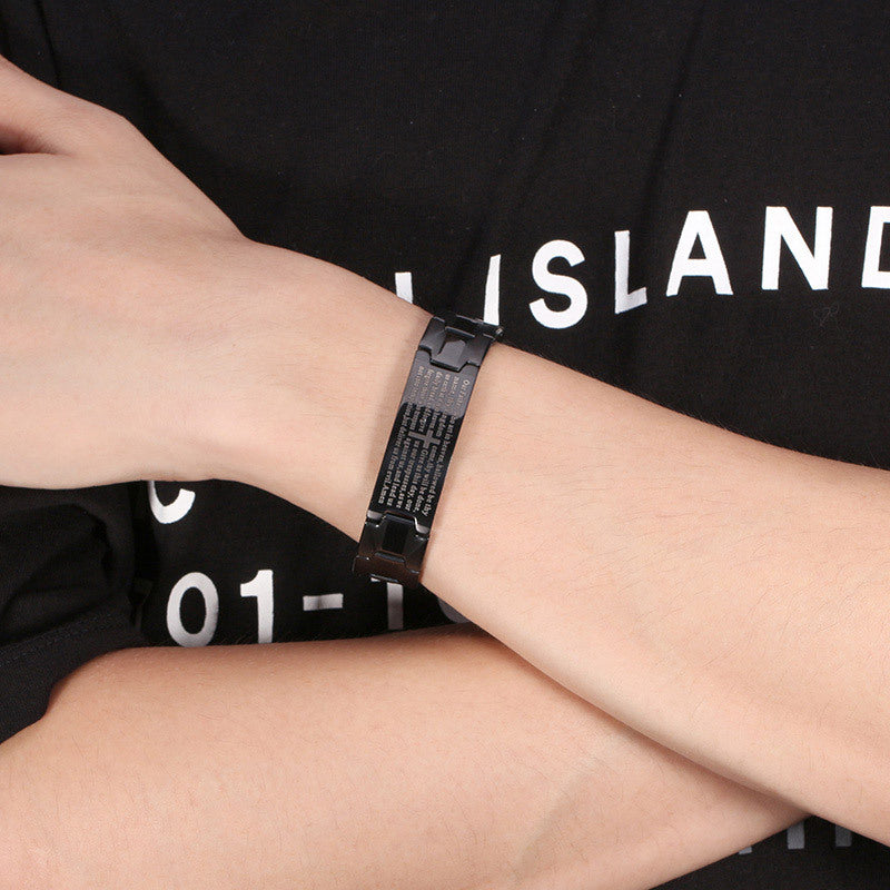 Person wearing a black bracelet on a black t-shirt with white text