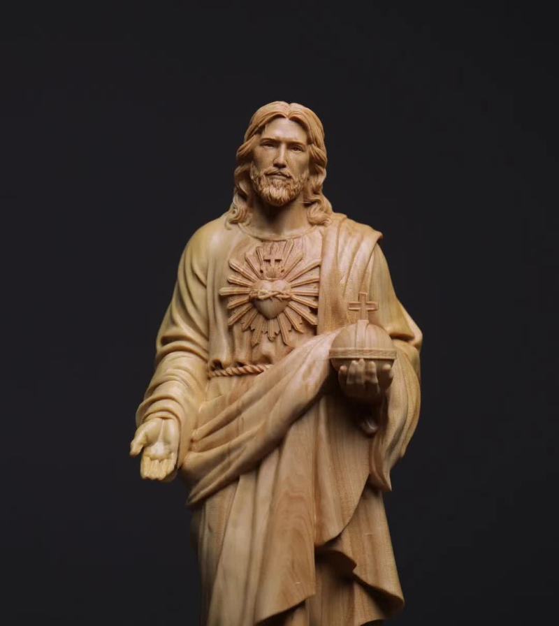 Wooden statue of a religious figure holding a heart symbol on a black background