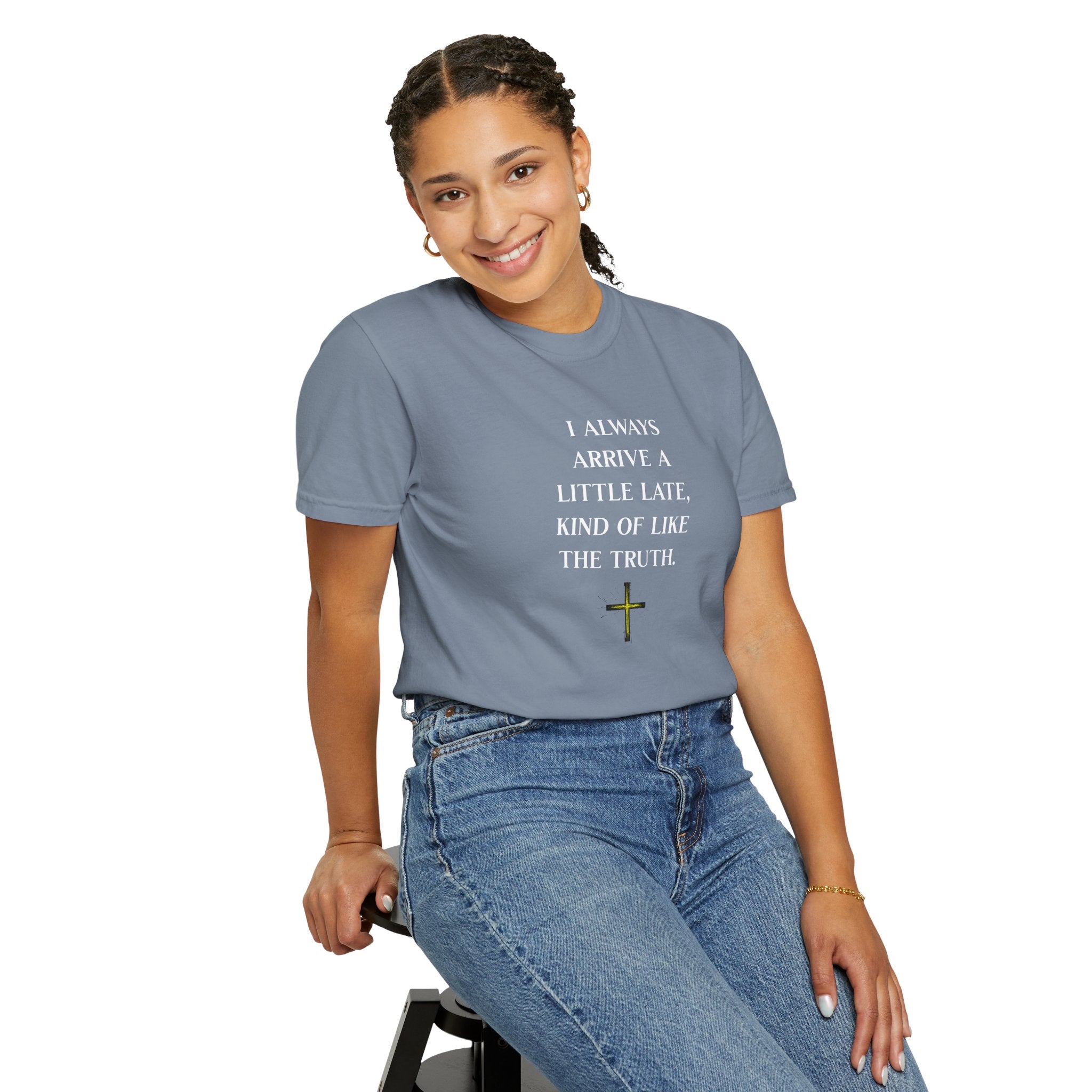 Person wearing a gray t-shirt with Arabic text and sitting on a stool against a white background