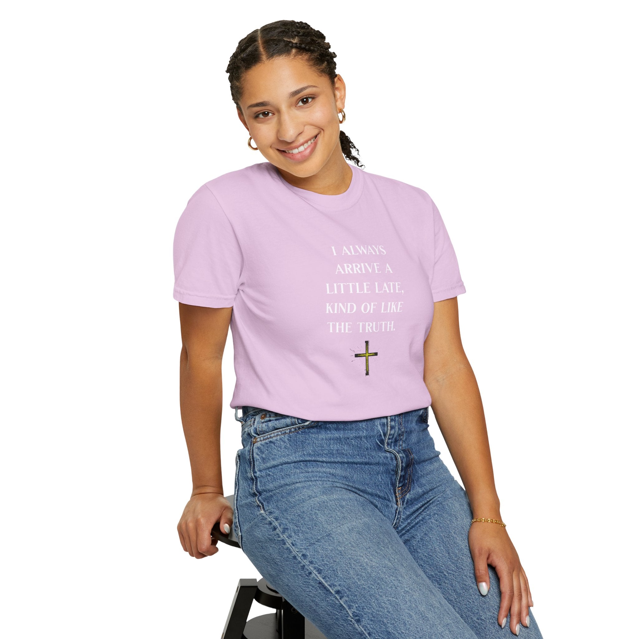 Person wearing a purple t-shirt with text and a cross symbol, sitting on a stool against a white background
