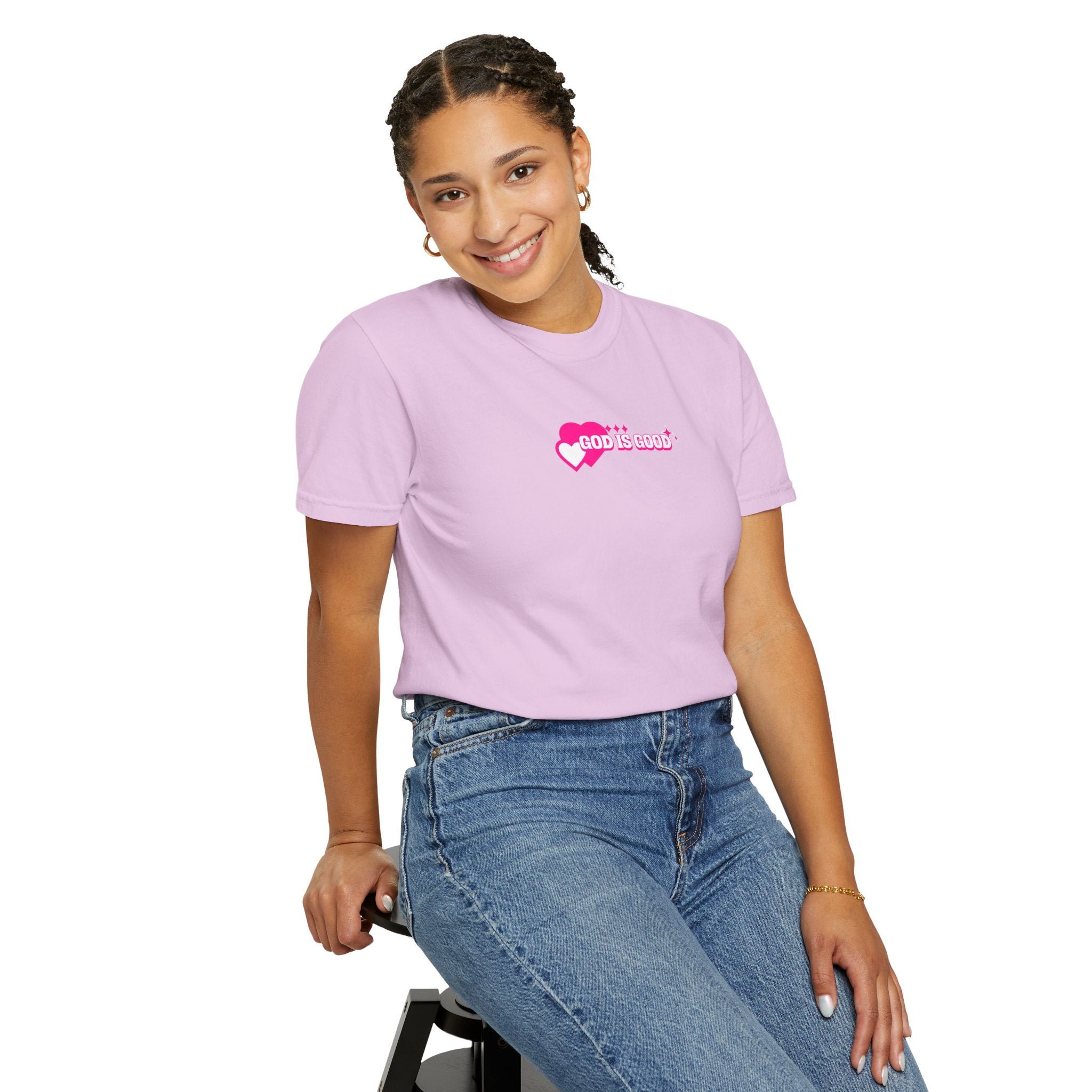 Person wearing a light purple t-shirt with a logo, sitting on a stool against a white background
