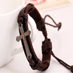 Brown braided leather bracelet with a silver cross charm on a white background