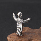 Silver pendant of a hooded figure on a dark background