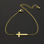Gold bracelet with a cross pendant on a black background