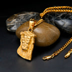 Gold necklace with a face pendant on a dark surface