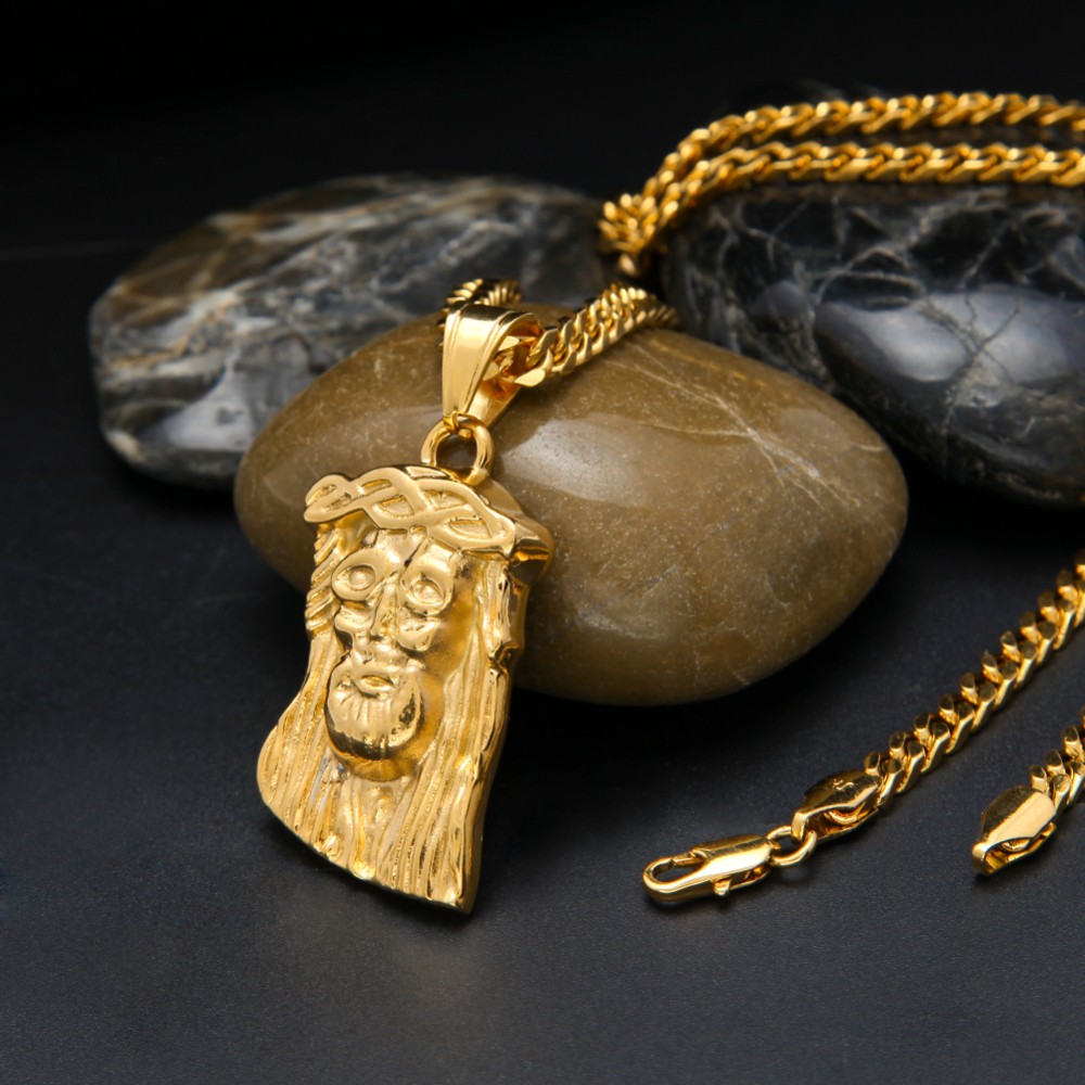 Gold necklace with a face pendant on a dark surface