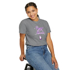 Person wearing a gray t-shirt with purple text and design, sitting on a stool against a white background
