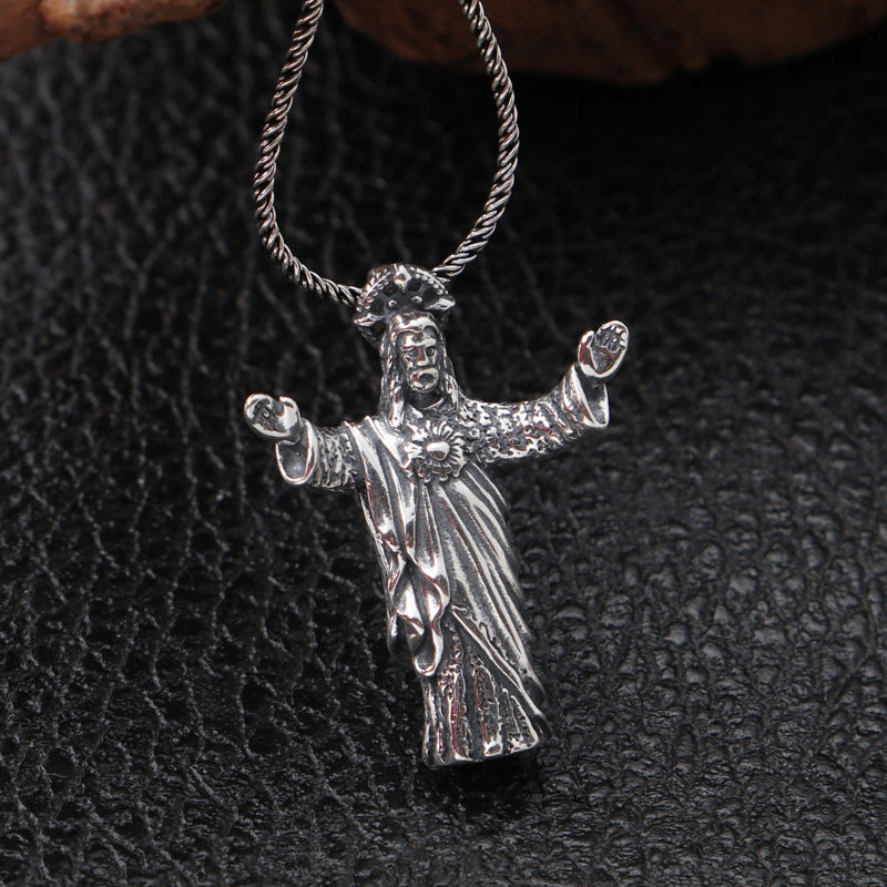 Silver Jesus pendant on a chain against a dark textured background