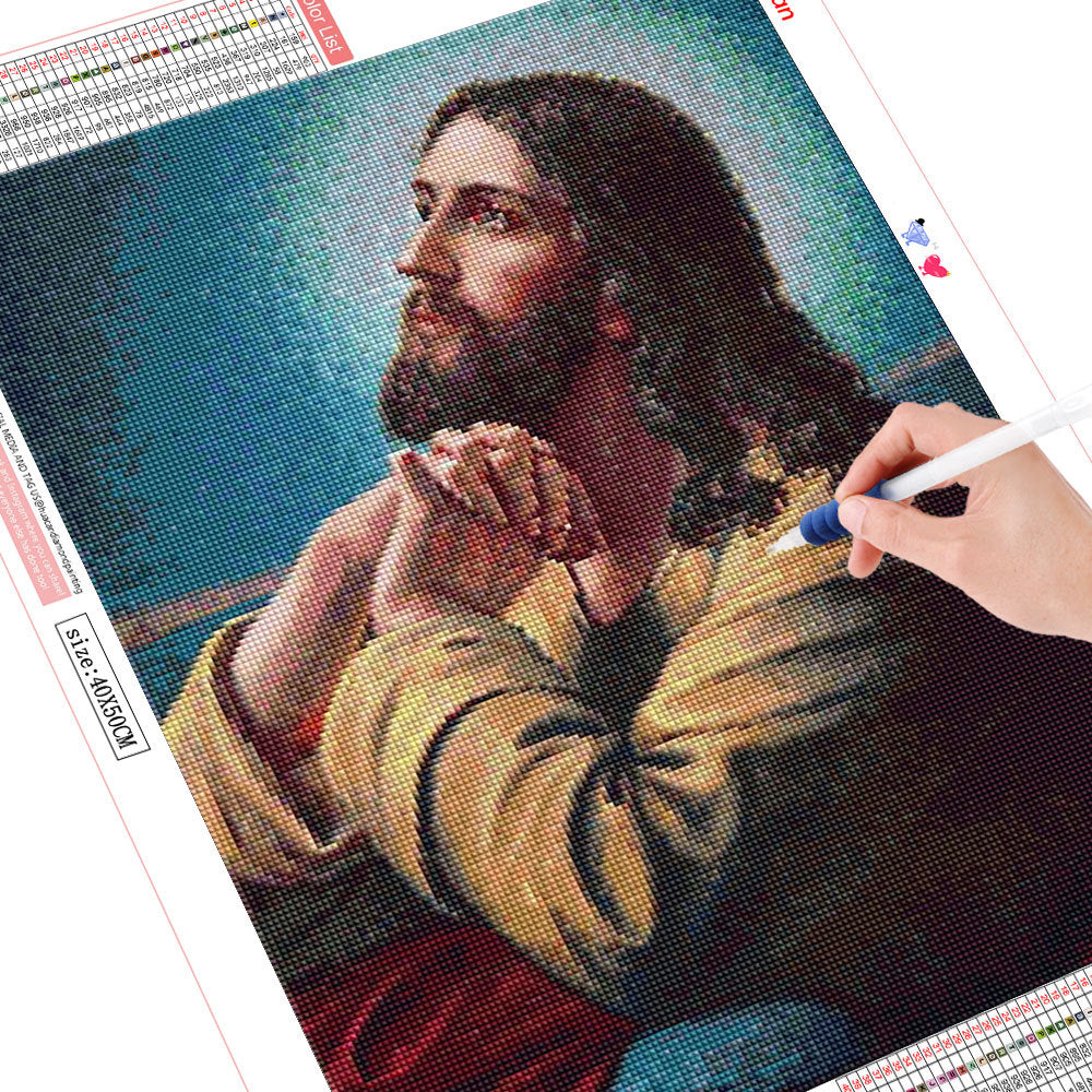 DIY diamond painting kit with a completed portrait of a bearded man, showing a hand using a tool to work on the design.