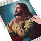 DIY diamond painting kit with a completed portrait of a bearded man, showing a hand using a tool to work on the design.