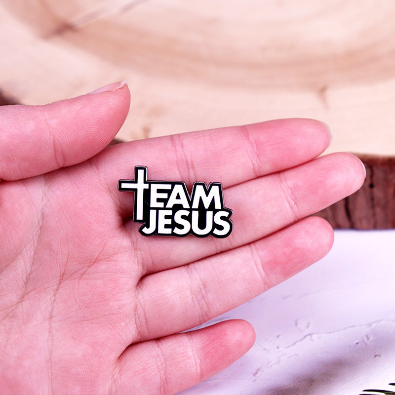 Hand holding a 'Team Jesus' badge with a cross symbol.