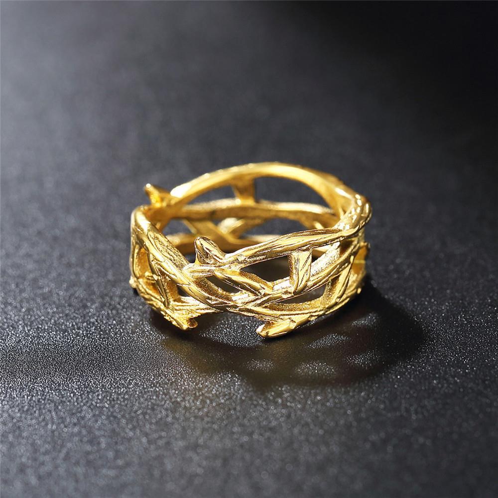 Gold ring with leaf design on a dark textured surface