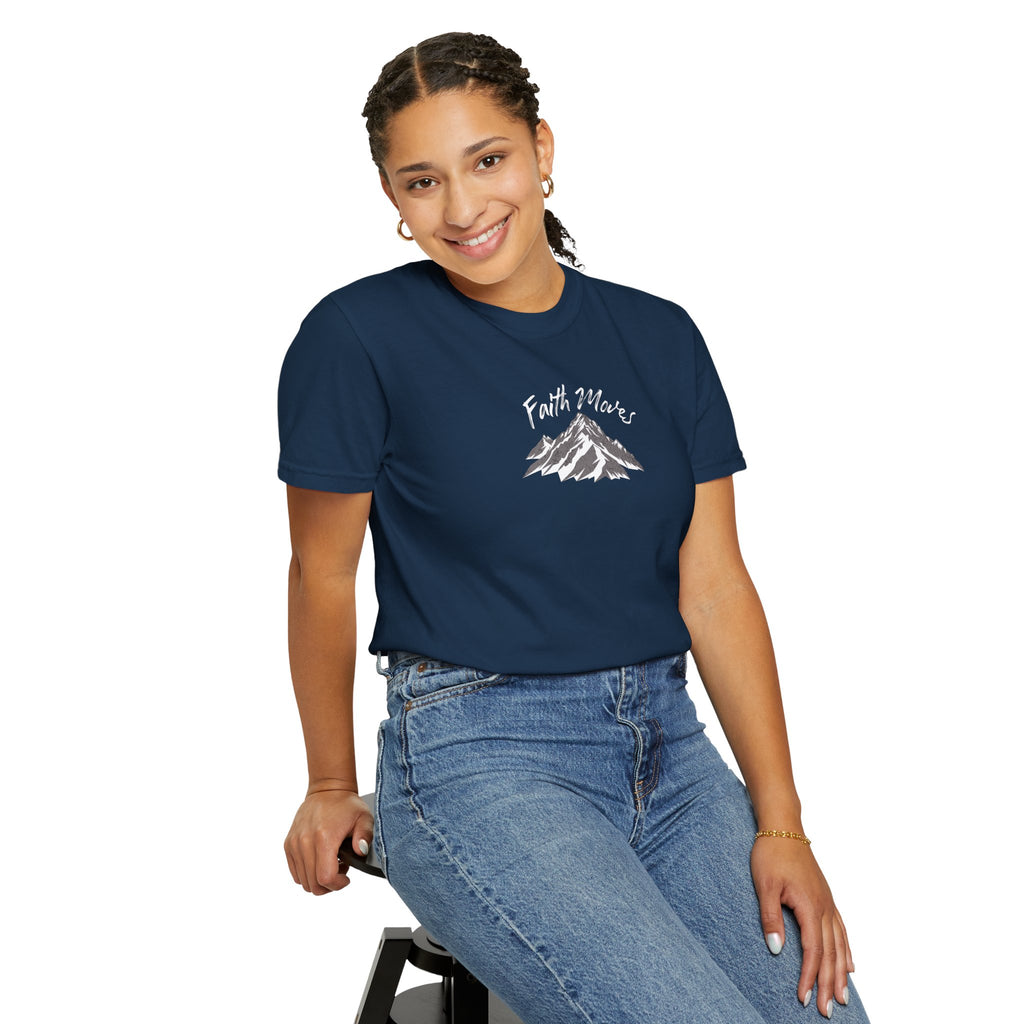 Person wearing a navy blue t-shirt with a mountain graphic and text, sitting on a stool against a white background.