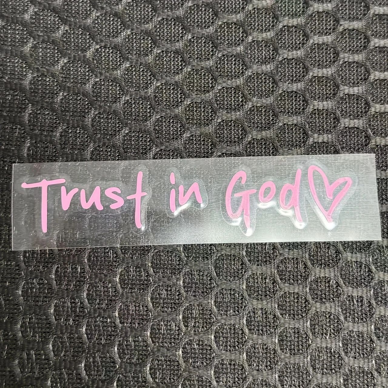 Clear decal with 'Trust in God' text on a textured black background