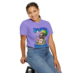 Person wearing a purple t-shirt with a graphic design sitting on a stool.