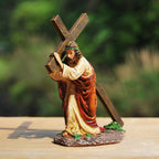 Statue of a person carrying a cross on a wooden surface with a blurred green background