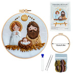 Embroidery DIY art kit with completed embroidery of a nativity scene, tools, and packaging on a white background.