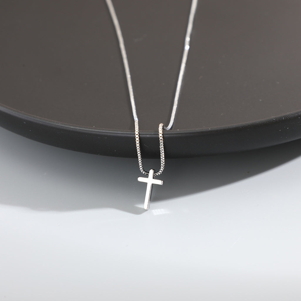 Silver cross necklace on a dark surface