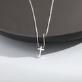 Silver cross necklace on a dark surface
